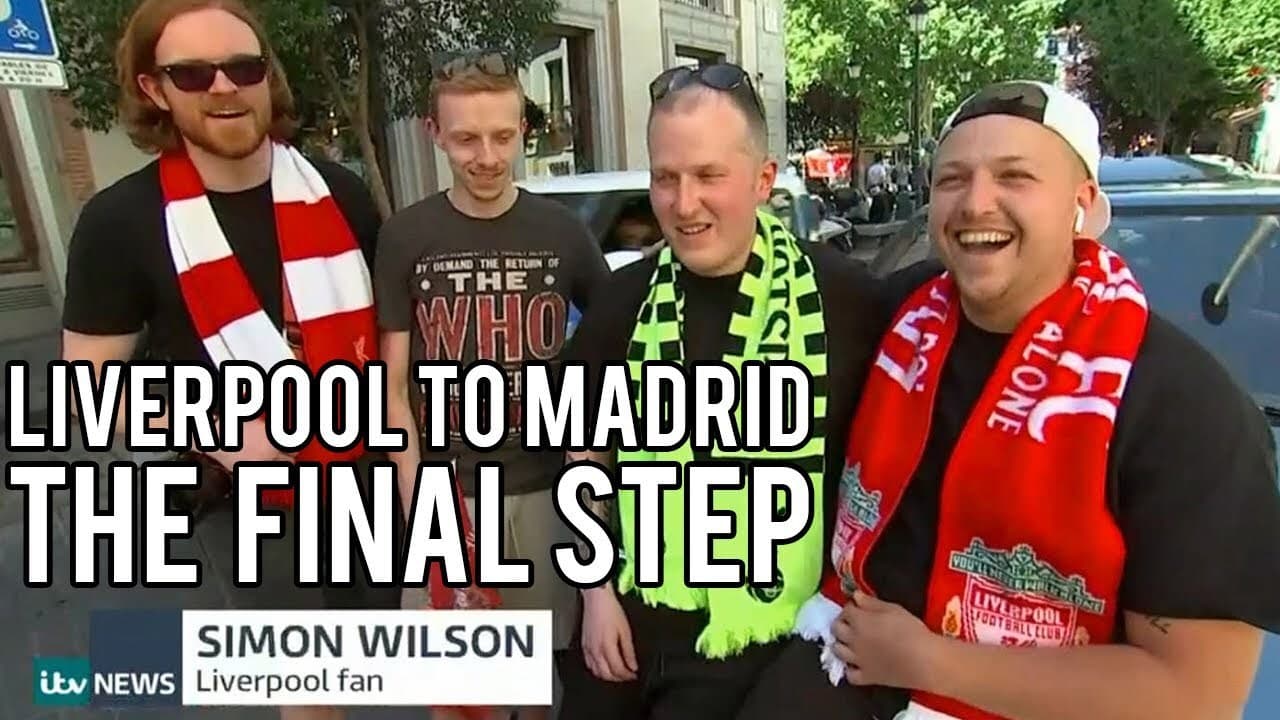 Four grinning lads in Liverpool scarves and one green and yellow scarf on a sunny Madrid street, in an ITV News interview captioned Simon Wilson, Liverpool fan