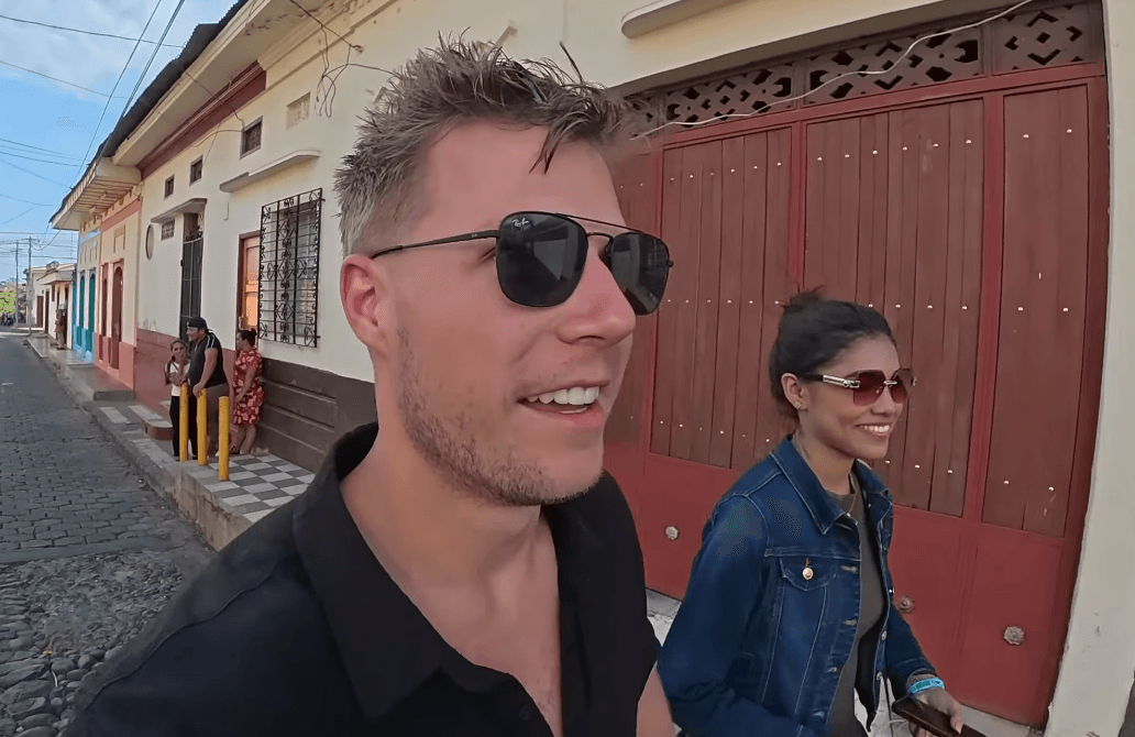 Kurt Caz walking down a cobblestone street past red wooden colonial doors in Nicaragua, screenshot from his 'I Surfed an Active Volcano in Nicaragua!' video